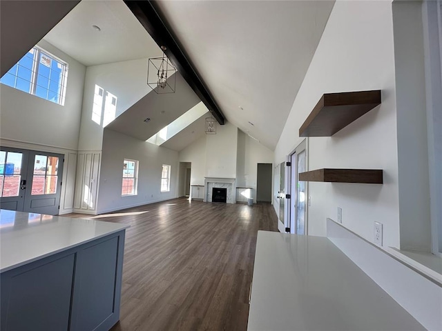 unfurnished living room featuring beam ceiling, a fireplace, dark wood-type flooring, and plenty of natural light