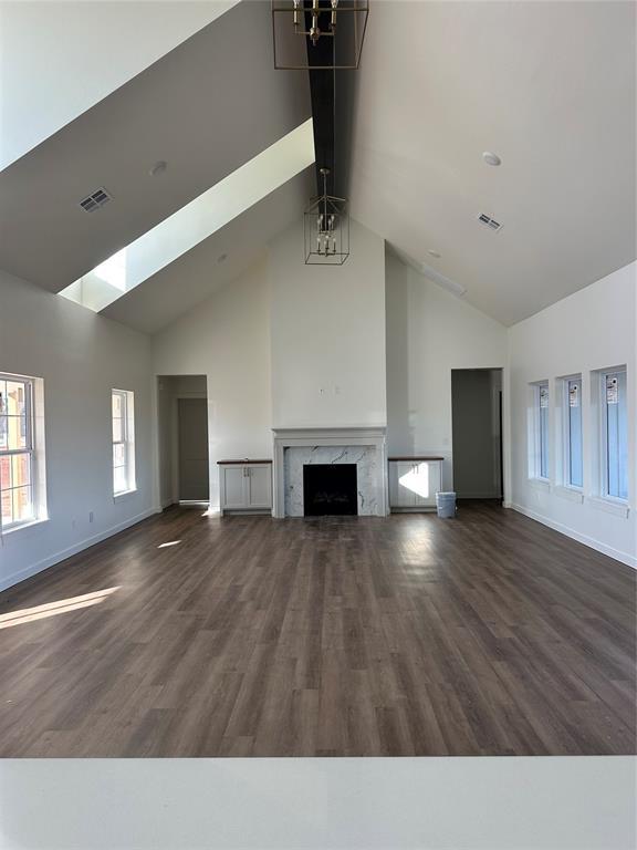 unfurnished living room featuring a high end fireplace, dark hardwood / wood-style flooring, and high vaulted ceiling