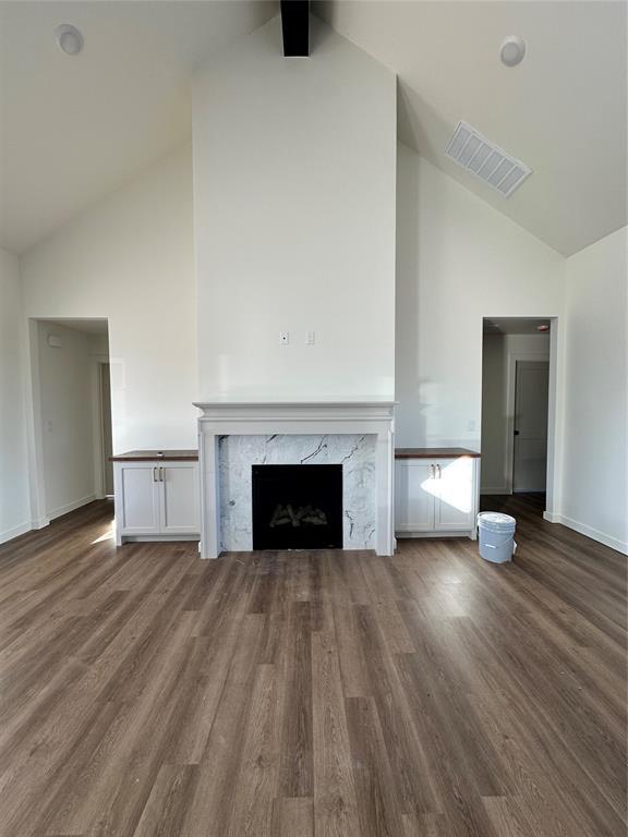 unfurnished living room with high vaulted ceiling, dark hardwood / wood-style floors, and a fireplace