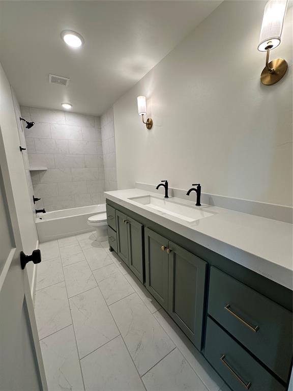 full bathroom with vanity, tiled shower / bath, and toilet