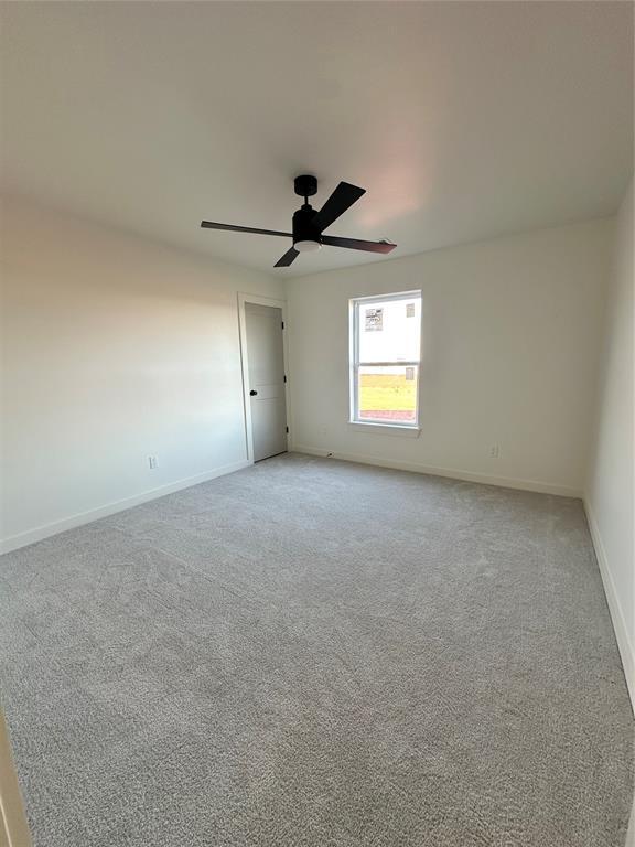 carpeted spare room with ceiling fan