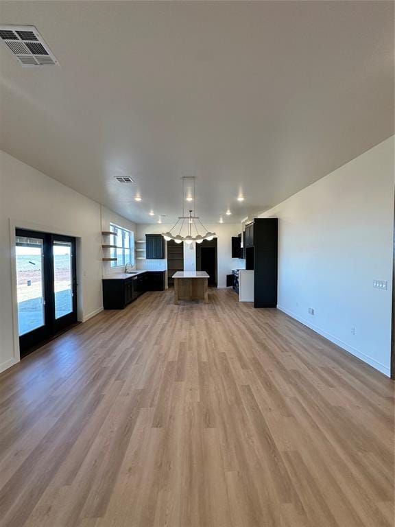 unfurnished living room featuring hardwood / wood-style floors, sink, and french doors