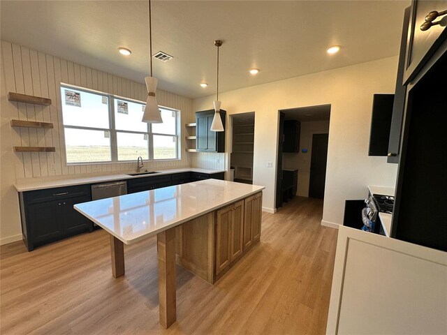 kitchen with a center island, sink, hanging light fixtures, light hardwood / wood-style flooring, and stainless steel appliances