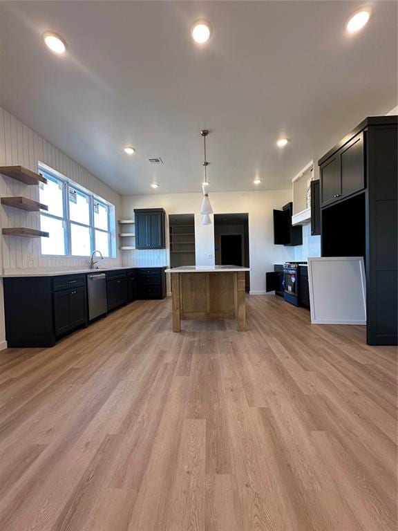 kitchen with sink, light wood-type flooring, stainless steel appliances, and hanging light fixtures