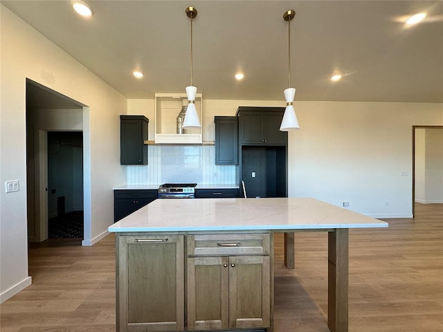 kitchen with light stone countertops, premium range hood, pendant lighting, a kitchen island, and stainless steel range with gas stovetop