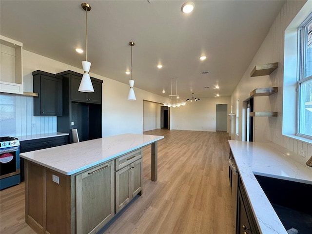 kitchen featuring sink, a center island, stove, and light stone counters