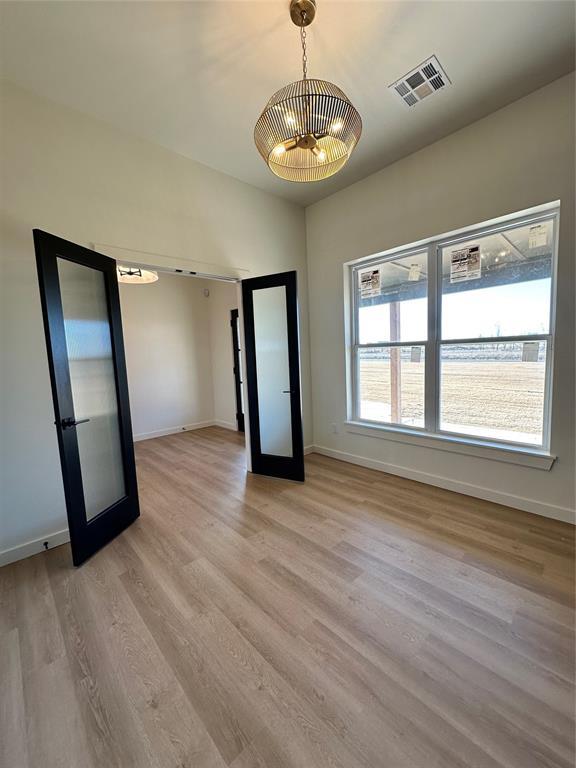 interior space featuring french doors, a chandelier, and light wood-type flooring