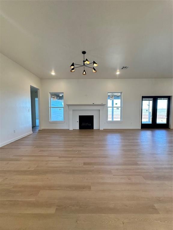 unfurnished living room with a chandelier and light wood-type flooring