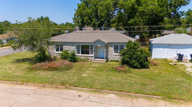 single story home with a front yard, an outbuilding, and a garage