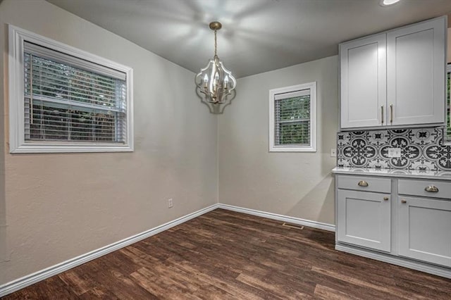 unfurnished dining area with dark hardwood / wood-style flooring and a healthy amount of sunlight