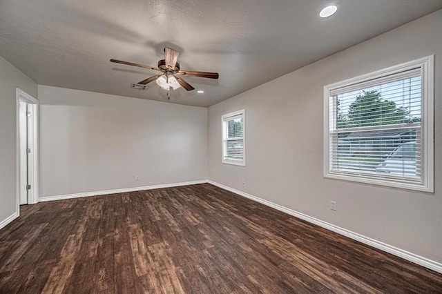 unfurnished room featuring a wealth of natural light, ceiling fan, and dark hardwood / wood-style floors