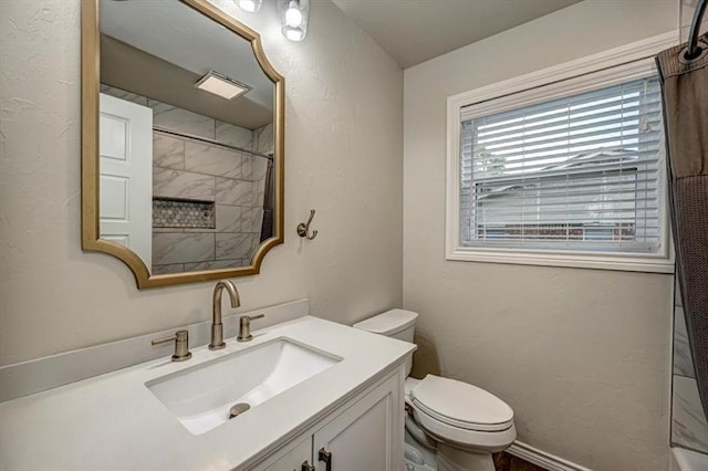 bathroom featuring a tile shower, vanity, and toilet