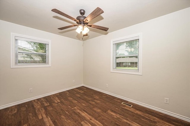 spare room featuring plenty of natural light, ceiling fan, and dark hardwood / wood-style flooring