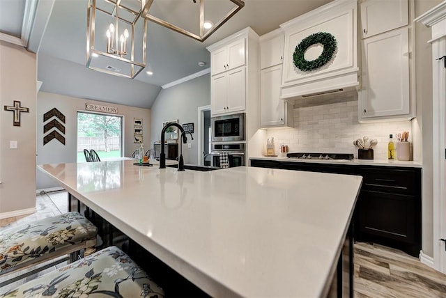 kitchen with pendant lighting, white cabinetry, a center island with sink, and stainless steel appliances