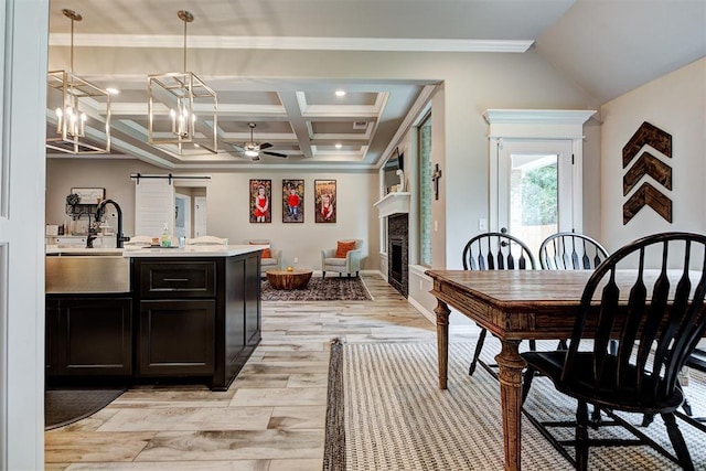 dining room with coffered ceiling, ceiling fan with notable chandelier, sink, a barn door, and beamed ceiling