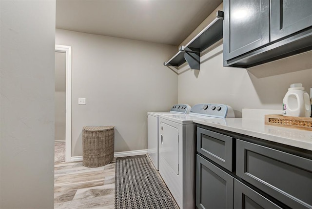 laundry area with washer and clothes dryer, light hardwood / wood-style floors, and cabinets