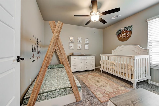 bedroom featuring carpet, ceiling fan, and a crib