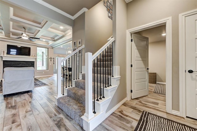 stairs with beam ceiling, ceiling fan, coffered ceiling, hardwood / wood-style flooring, and ornamental molding