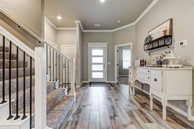 foyer with crown molding and light hardwood / wood-style flooring