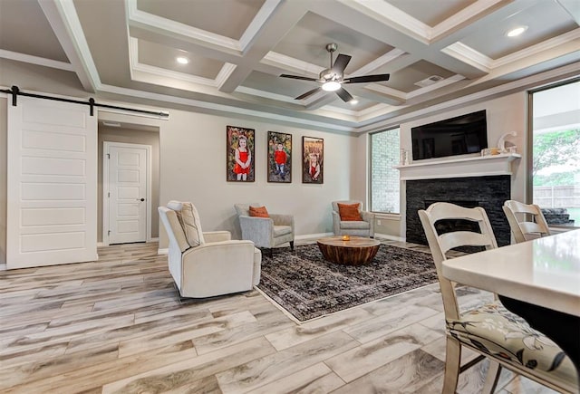 living room with a fireplace, a barn door, light hardwood / wood-style floors, and coffered ceiling