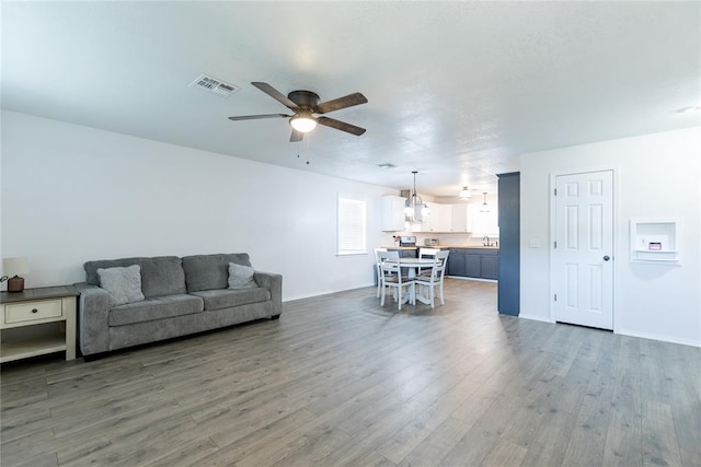 living room featuring dark hardwood / wood-style floors, ceiling fan, and sink