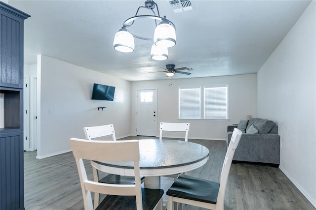 dining room with ceiling fan with notable chandelier and dark hardwood / wood-style flooring