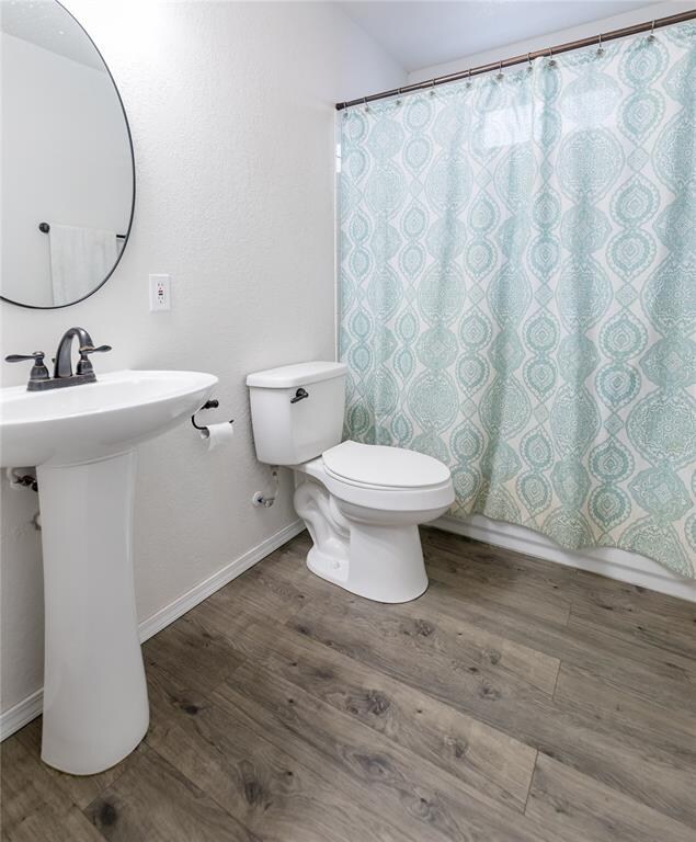 bathroom featuring hardwood / wood-style floors, a shower with curtain, and toilet