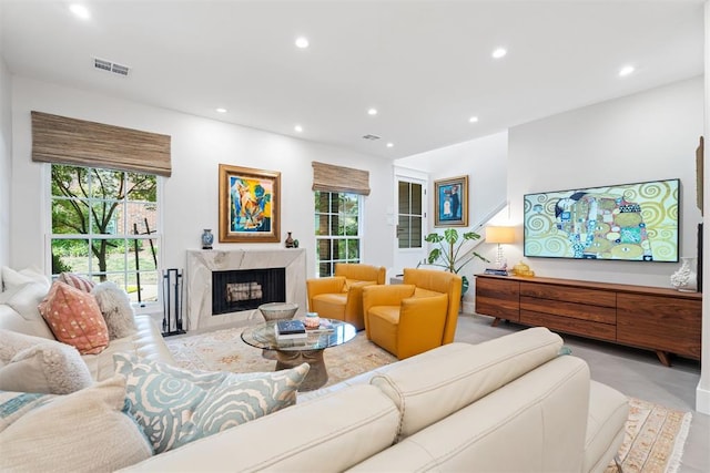 living room featuring a high end fireplace and a healthy amount of sunlight