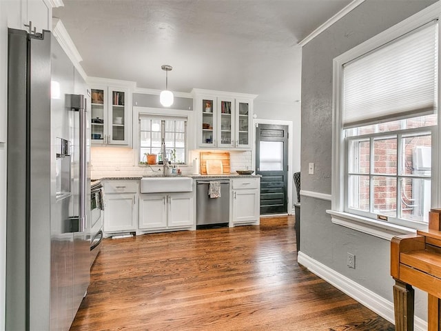 kitchen with white cabinetry, sink, hanging light fixtures, stainless steel appliances, and tasteful backsplash