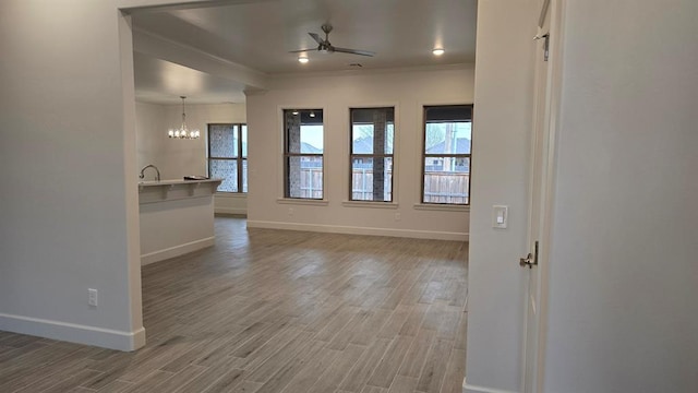 spare room with ceiling fan with notable chandelier, wood-type flooring, and plenty of natural light