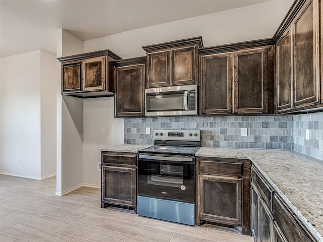 kitchen with light stone countertops, appliances with stainless steel finishes, and tasteful backsplash