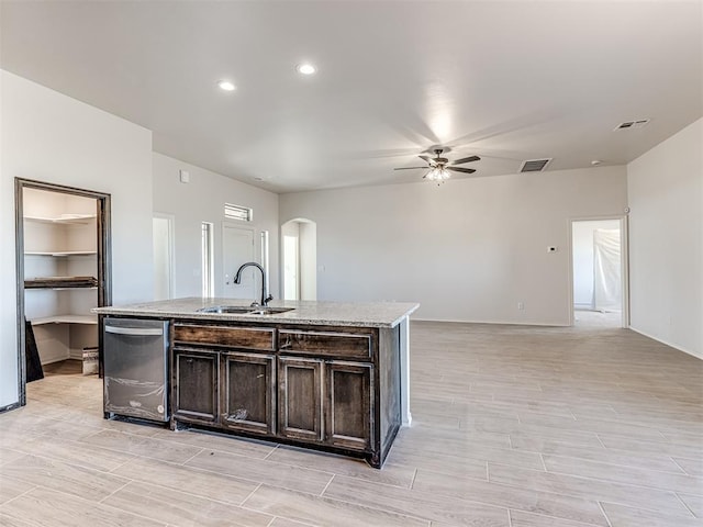 kitchen with ceiling fan, dishwasher, sink, dark brown cabinets, and a center island with sink