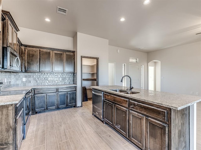 kitchen with dark brown cabinets, sink, stainless steel appliances, and an island with sink