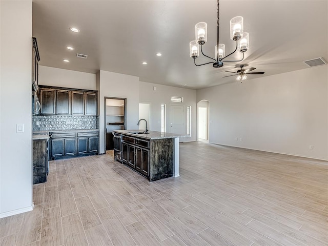 kitchen with dark brown cabinetry, sink, pendant lighting, a center island with sink, and light hardwood / wood-style floors