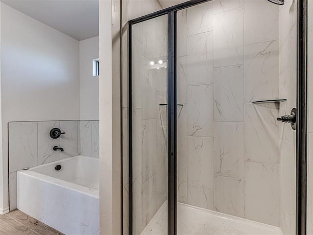 bathroom with wood-type flooring and shower with separate bathtub