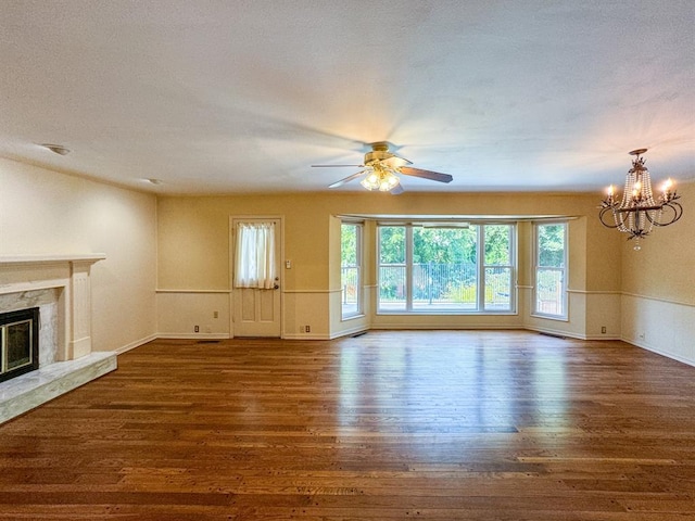 unfurnished living room with ceiling fan with notable chandelier, dark hardwood / wood-style flooring, and a high end fireplace