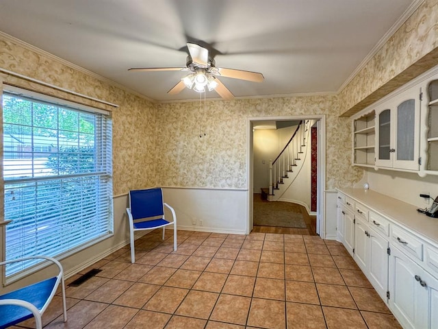 interior space with ceiling fan, light tile patterned floors, and ornamental molding