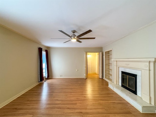 unfurnished living room featuring built in shelves, ceiling fan, light hardwood / wood-style flooring, and crown molding