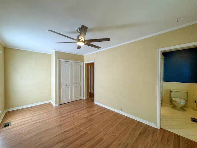 unfurnished bedroom featuring connected bathroom, ceiling fan, a closet, and light hardwood / wood-style floors