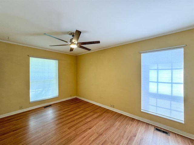 empty room featuring plenty of natural light, light wood-type flooring, and crown molding