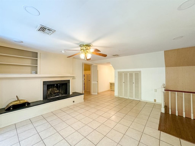 unfurnished living room featuring ceiling fan, built in features, and light tile patterned floors