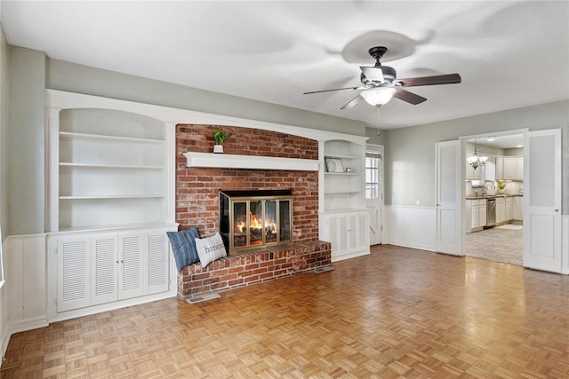 unfurnished living room featuring a fireplace, built in shelves, and light parquet floors