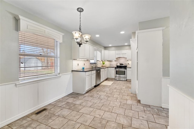 kitchen with white cabinets, sink, hanging light fixtures, decorative backsplash, and appliances with stainless steel finishes