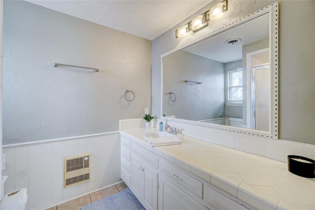 bathroom with tile patterned floors, heating unit, vanity, and walk in shower