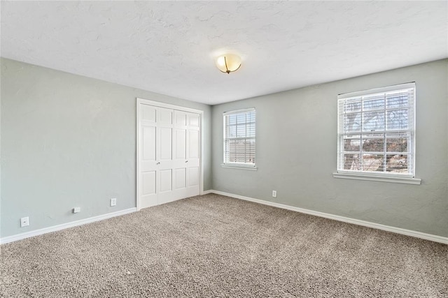 unfurnished bedroom with carpet, a closet, and multiple windows