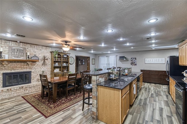 kitchen featuring a center island with sink, light wood-type flooring, sink, and a textured ceiling