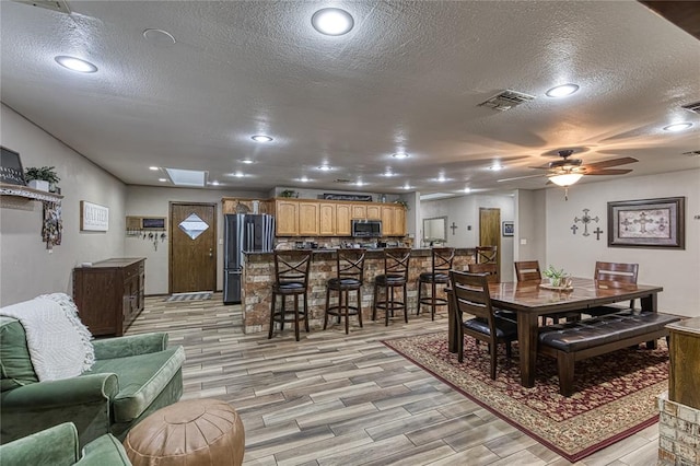 dining space featuring ceiling fan, light hardwood / wood-style floors, and a textured ceiling