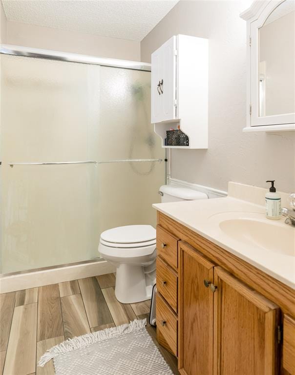 bathroom featuring hardwood / wood-style flooring, vanity, walk in shower, and a textured ceiling