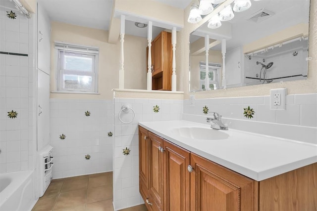 bathroom featuring tiled shower / bath, vanity, tile patterned floors, and tile walls