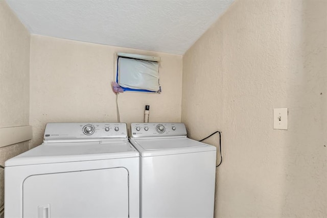 clothes washing area with washer and dryer and a textured ceiling